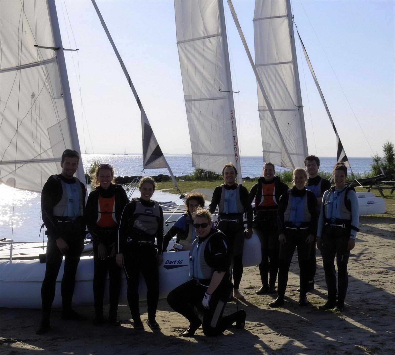 Groep in wetsuits samen op het strand bij een catamaran van Haddock Watersport